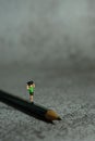 Miniature people toy figure photography. A boy running above pencil with grey cloudy background Royalty Free Stock Photo