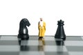 Miniature people toy figure photography. Defense attack strategy concept. A Sultan standing above chess board in between horse and Royalty Free Stock Photo