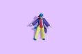 Miniature people toy figure photography. Full body of a clown wearing huge tie and suit. Isolate on purple background