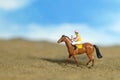 Miniature people toy figure photography. A jockey man riding horse at farm, sand desert land field Royalty Free Stock Photo