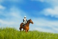 Miniature people toy figure photography. A jockey man riding horse at meadow field for training Royalty Free Stock Photo