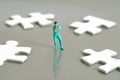 Miniature people toy figure photography. A men doctor or nurse thinking in the middle of four white puzzle piece standing on Royalty Free Stock Photo