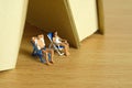 Miniature people toy figure photography. Men and girl couple relaxing seat at beach chair under book tent