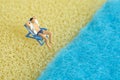 Miniature people toy figure photography. Men relaxing at beach chair in front of wavy beach Royalty Free Stock Photo