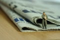 Miniature people toy figure photography. A military mail officer holding news pack envelope standing above newspaper