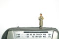 Miniature people toy figure photography. A military mail officer holding news pack envelope standing above radio fm device.