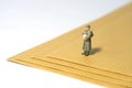 Miniature people toy figure photography. A military mail officer holding news pack standing above brown envelope. Isolated on