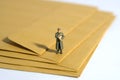 Miniature people toy figure photography. A military mail officer holding news pack standing above brown envelope. Isolated on