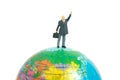 Miniature people toy figure photography. Rule the world concept. A businessman standing above globe while raise his hand. Isolated Royalty Free Stock Photo