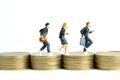 Miniature people toy figure photography. School admission budget concept. Pupils running above golden coin stack cent money,