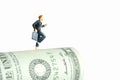 Miniature people toy figure photography. School admission budget concept. Young girl pupil running above rolled dollar money paper