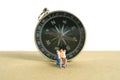 Miniature people toy figure photography. Travel destination, Men relaxing at beach chair with black compass, isolated on white Royalty Free Stock Photo