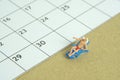 Miniature people toy figure photography. Travel plan schedule concept, men relaxing at beach chair with calendar Royalty Free Stock Photo