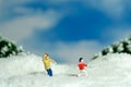 Miniature people toy figure photography. Winter holiday. Kids brother and sister playing snowball throwing