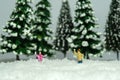 Miniature people toy figure photography. Winter holiday. Kids brother and sister playing snowball throwing in the pine fir forest