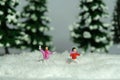 Miniature people toy figure photography. Winter holiday. Kids brother and sister playing snowball throwing in the pine fir forest