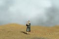 Miniature people toy figure photography. A woman holding photo frame, searching missing person in the desert