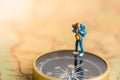 Miniature people: traveler stand on the compass to tell the direction of travel. Use as a business travel concept