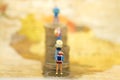 Miniature people: travelers with backpack standing on top stack of coins. Image use for travel business concept Royalty Free Stock Photo