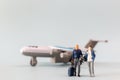Miniature people, travelers embarks on a delightful vacation, gleefully boarding a tiny airplane Royalty Free Stock Photo