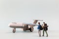 Miniature people, travelers embarks on a delightful vacation, gleefully boarding a tiny airplane Royalty Free Stock Photo