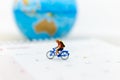 Miniature people : Travelers riding bicycle around the world. Image use for background traveling , business concep