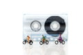Miniature people : Travelers riding bicycle with Audio cassette Royalty Free Stock Photo