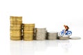 Miniature people : Travelers riding bicycle with stack of coins. Image use for background traveling and healthy, business concepts