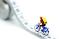 Miniature people : travelers riding bicycle with Tape Measure. Royalty Free Stock Photo