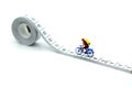 Miniature people : travelers riding bicycle with Tape Measure. Royalty Free Stock Photo