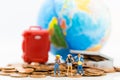 Miniature people : Travelers stand on a pile of coins and have a red suitcase, world map for background. Image use for travel, Royalty Free Stock Photo