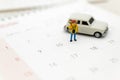 Miniature people, travelers standing on the calendar, mark date for traveling to destination. Used in the travel business concept