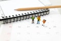 Miniature people, travelers standing on the calendar, mark date for traveling to destination. Used in the travel business concept