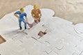 Miniature people trying to complete the last jigsaw puzzle piece, teamwork concept. Royalty Free Stock Photo