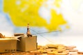 Miniature people, People use the fishing rod to take money from the floor and drop stack coins in the box. Used as Hacking strate Royalty Free Stock Photo