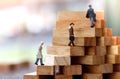 Miniature people walking on step of Wood block stack. growth in business concept.