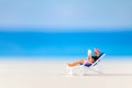 Miniature people , a woman relaxing on a deck chair and reading a book Royalty Free Stock Photo