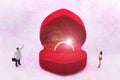 Miniature people : Women and men stand opposite, between with wedding ring. Image use for express love, Valentine`s day concept Royalty Free Stock Photo