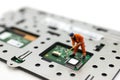 Miniature people: Worker repairing circuit board ,electronics repair. Use image for support and maintenance business