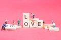 Miniature people : Worker team building word ` Love `