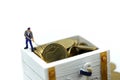 Miniature people : worker team and businessman with treasure coffer of gold.