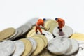 Miniature people: Worker working on stack of coins, income from work. Image use for business concept Royalty Free Stock Photo