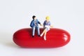 Miniature peoples on red capsule Royalty Free Stock Photo