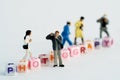 Miniature Photographers taking pictures behind a Group Of Letters forming Word Spelling