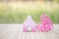 Miniature pink wooden house with pink wooden heart design over blurred green garden background, outdoor day light Royalty Free Stock Photo