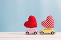 Miniature pink and yellow cars carrying heart cushions