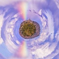 Miniature planet with a rainbow crossing the blue sky