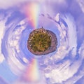 Miniature planet with a rainbow crossing the blue sky Royalty Free Stock Photo