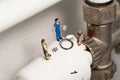 Miniature Plumbers Repairing A Thermostat
