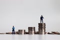 Miniature police holding loudspeakers on a pile of coins and miniature police standing next to a pile of coins.